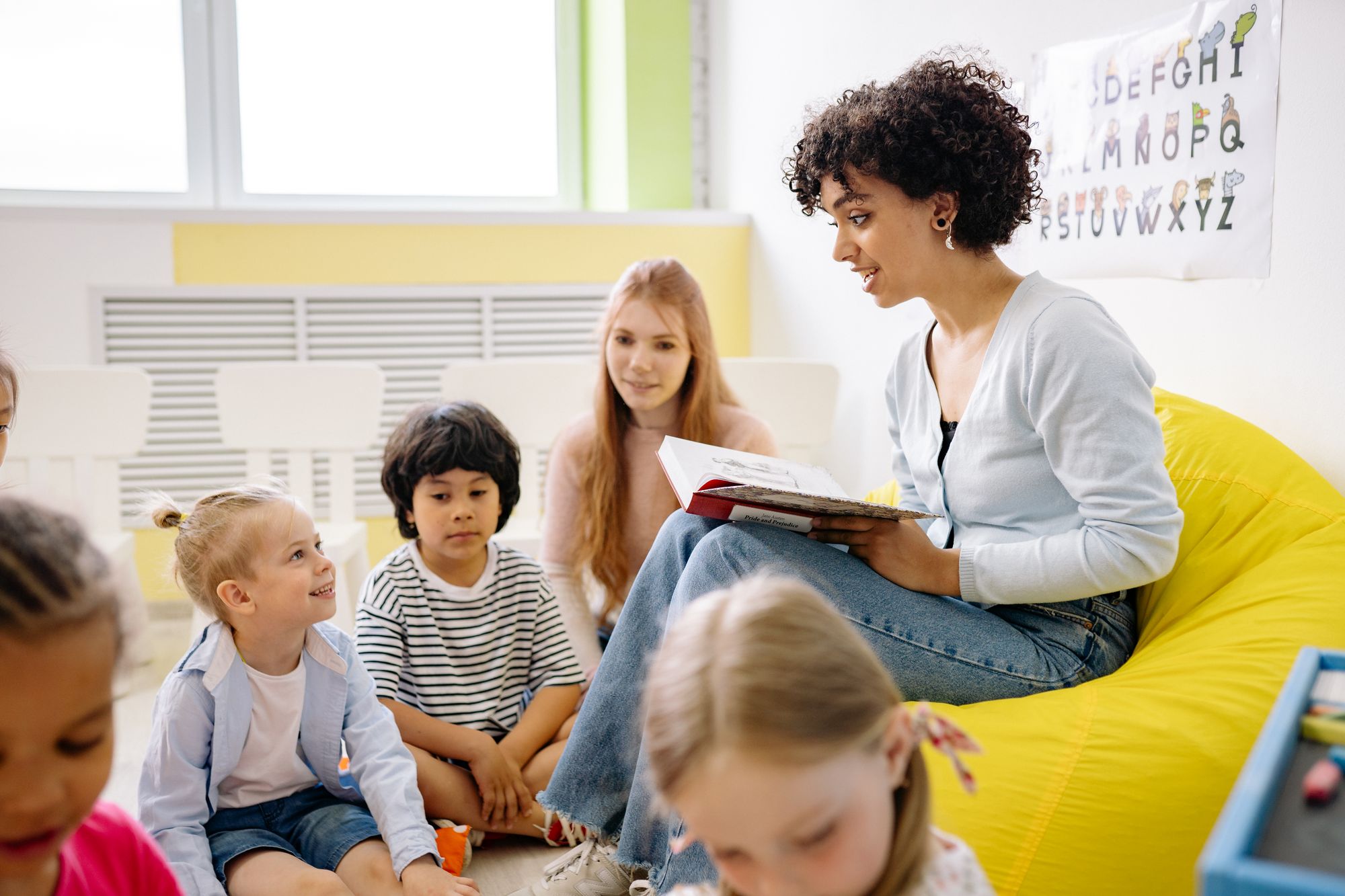 A primary-school teacher reading with a group of young children